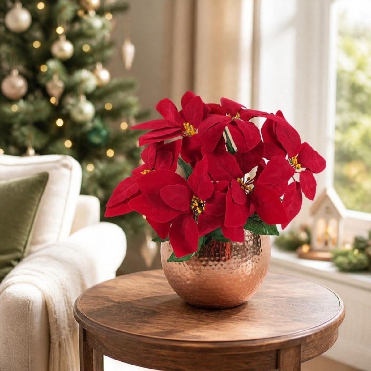 Artificial red poinsettia in a hammered copper planter on a side table