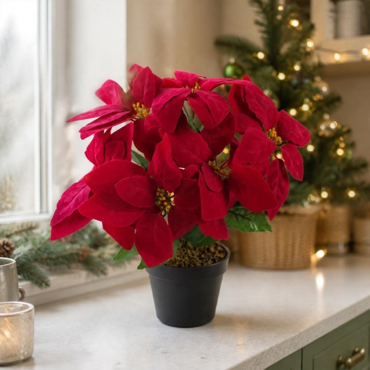 Artificial red poinsettia in a black pot on a kitchen windowsill