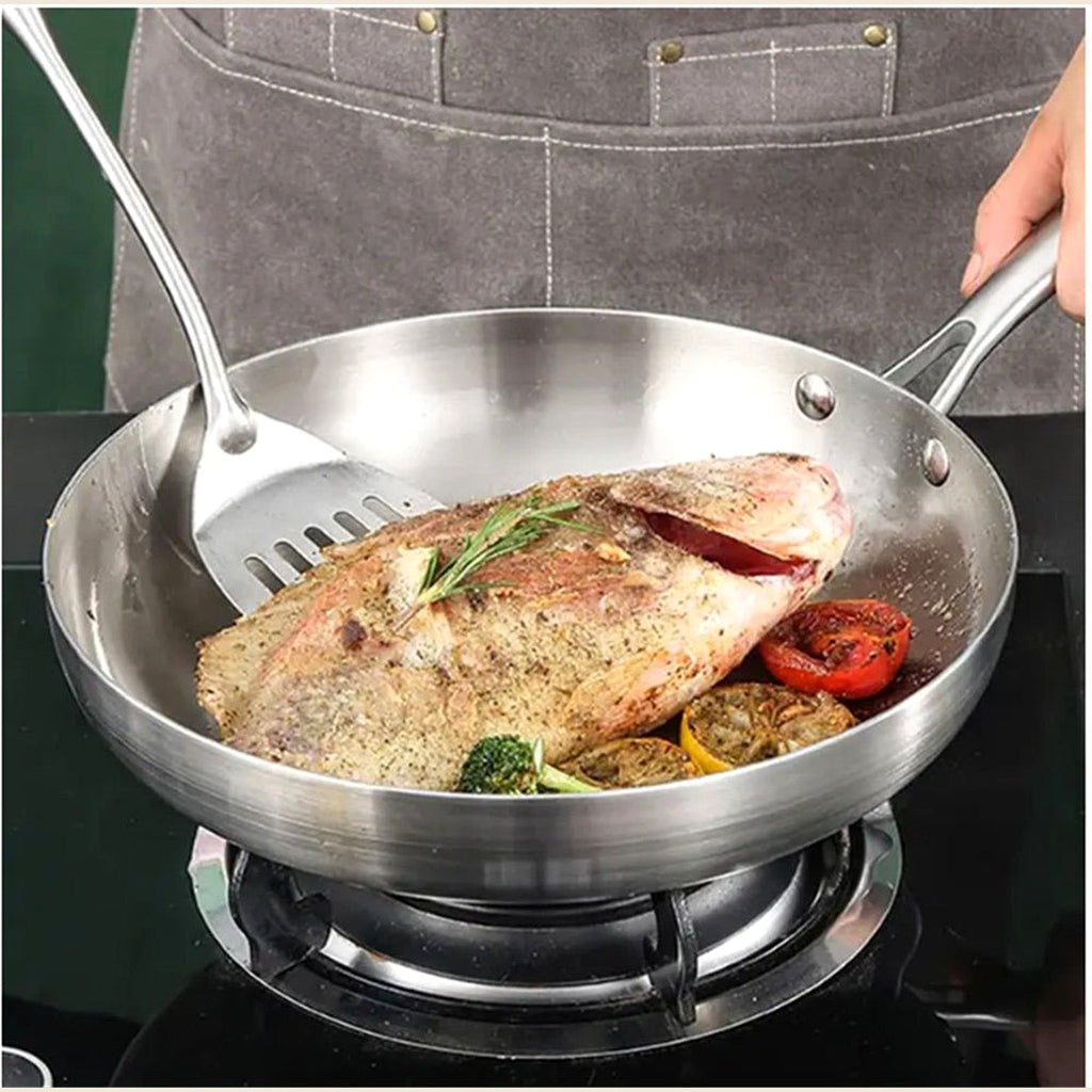 Fish fillet frying in a stainless steel pan on a gas hob
