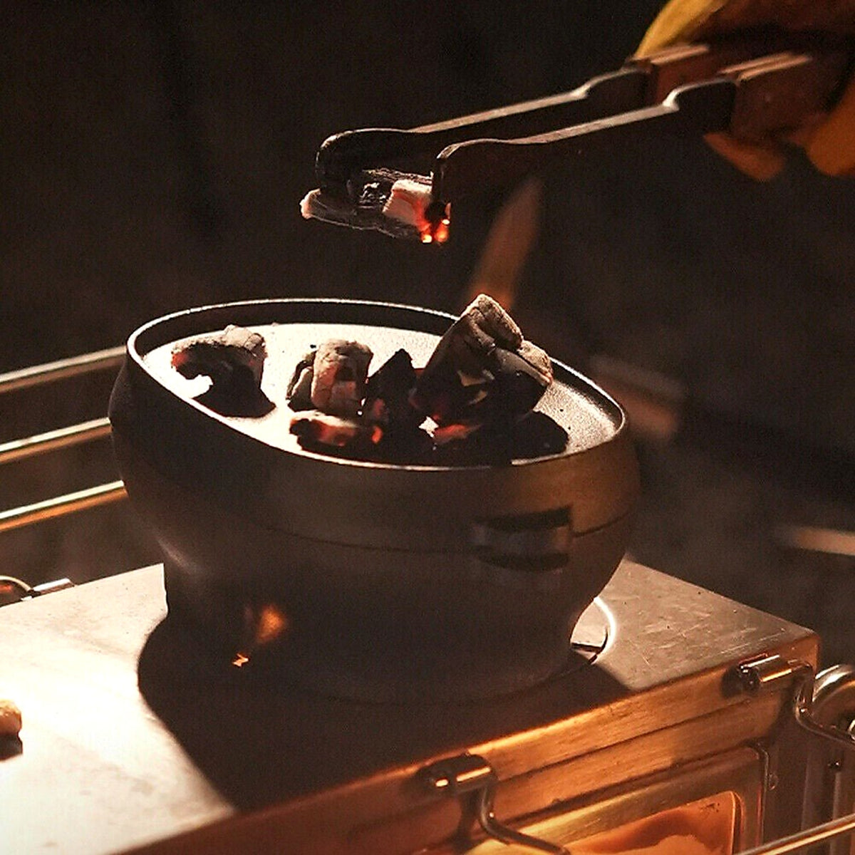 Cast iron Dutch oven on hot coals with tongs