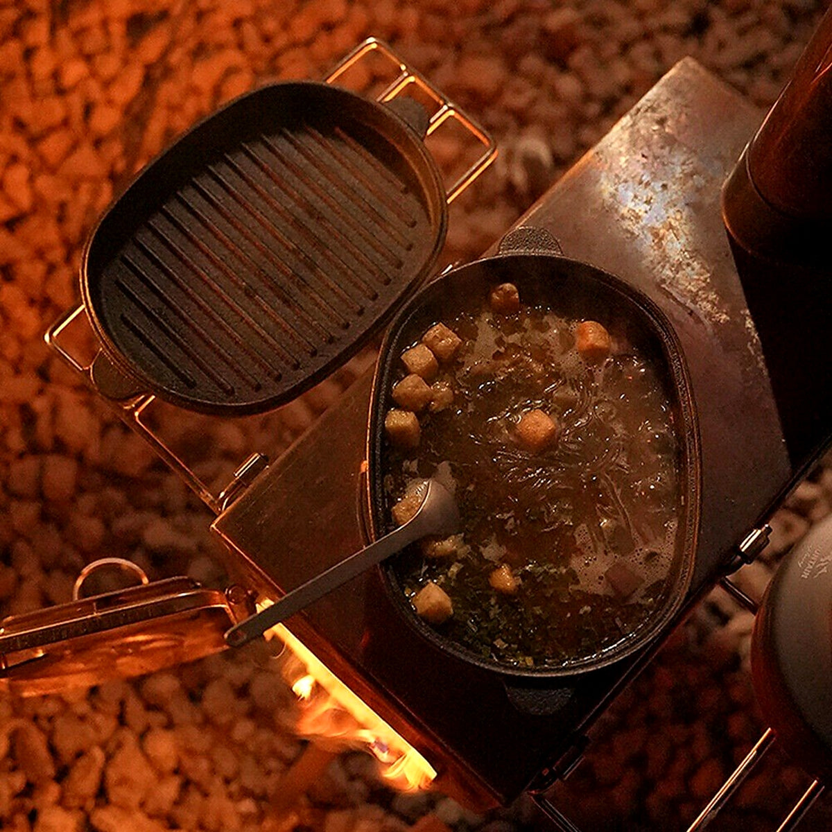 Cast iron Dutch oven cooking over a campfire with the grill lid