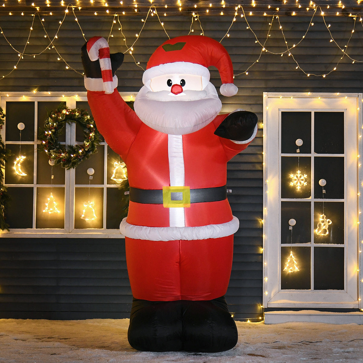 Lit inflatable Santa outside a decorated house at night
