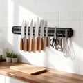 Magnetic knife bar holding knives and kitchen tools on a kitchen wall
