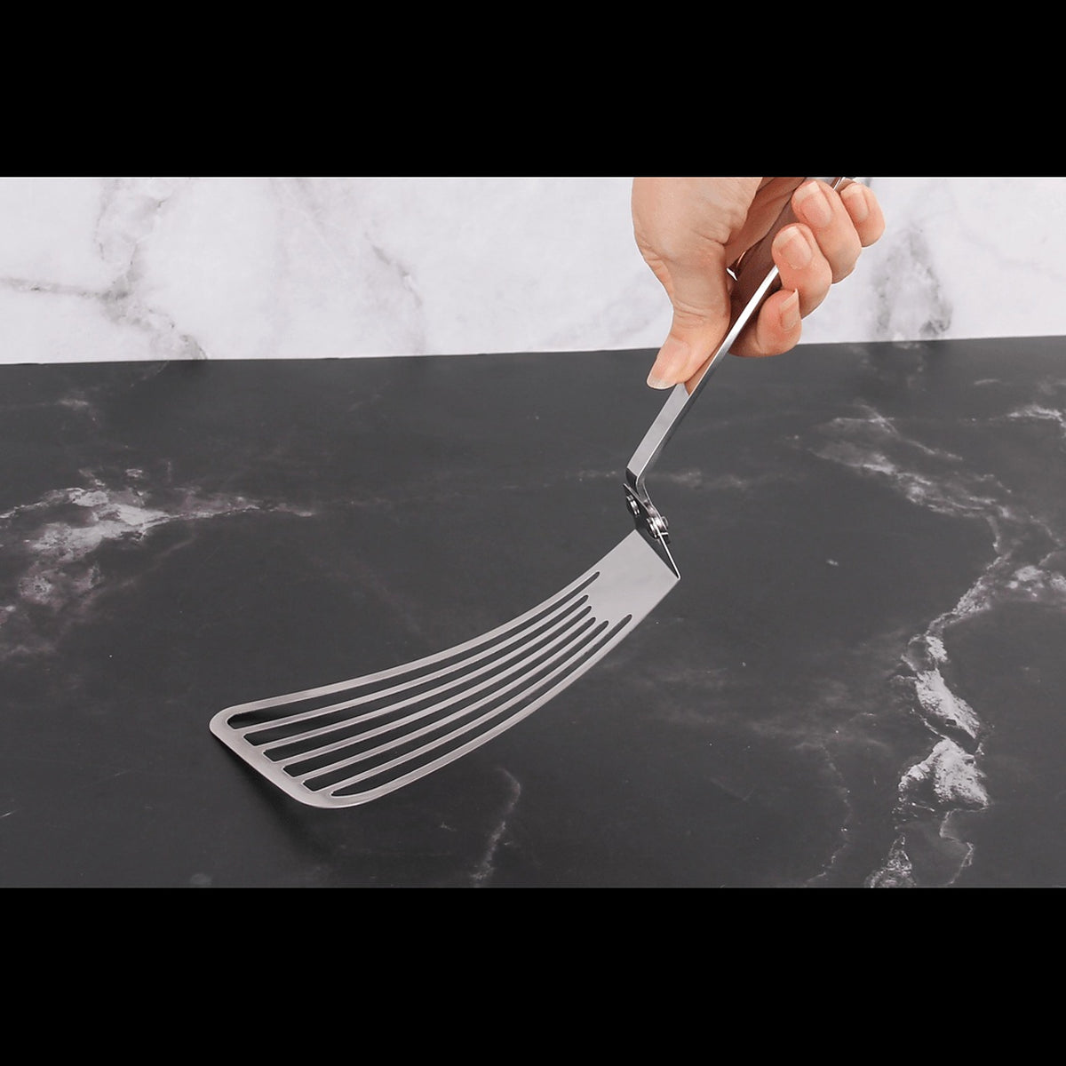 Slotted turner held over a marble worktop