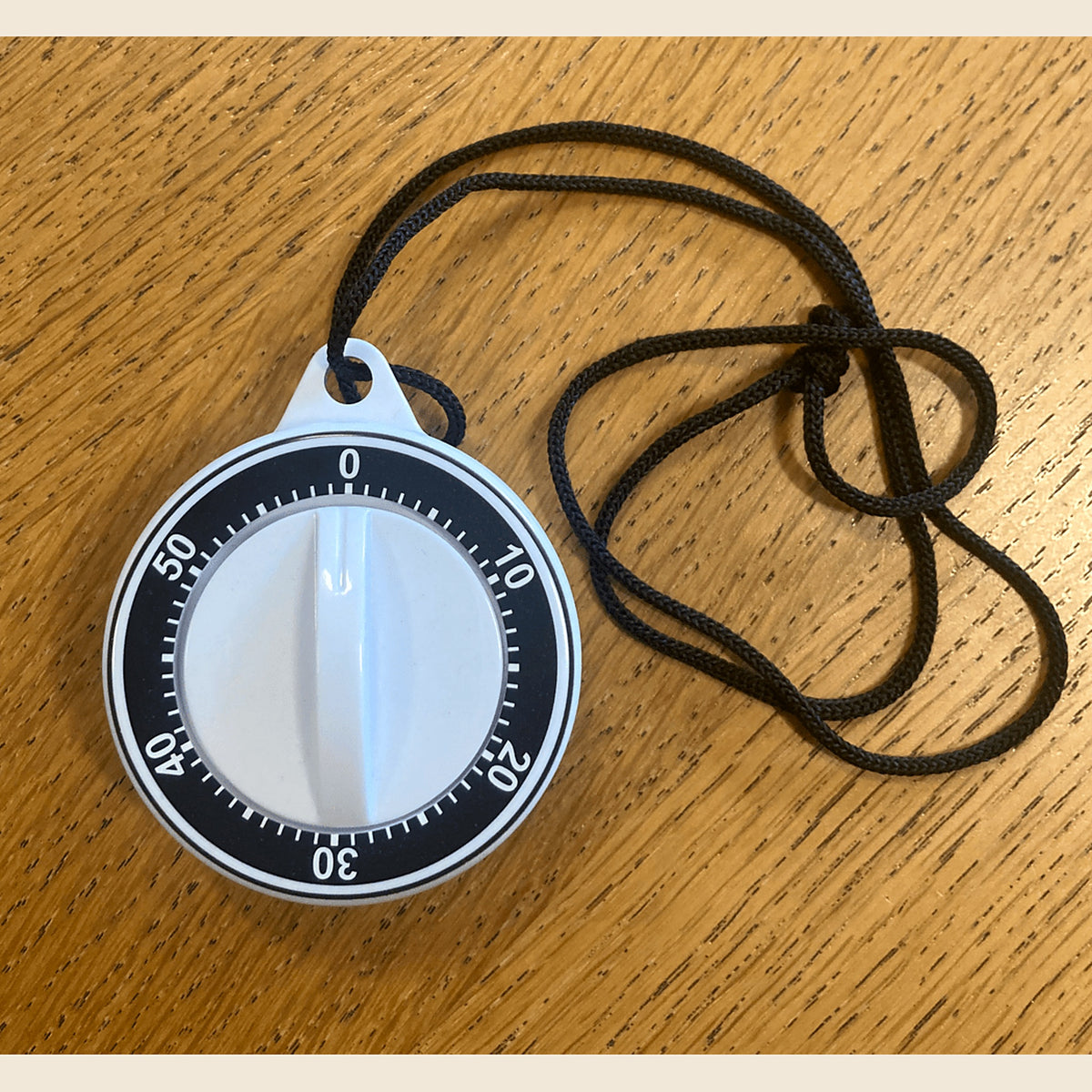 Kitchen timer with neck cord on a wooden table