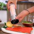 Seasoning salmon with the salt and pepper grinder