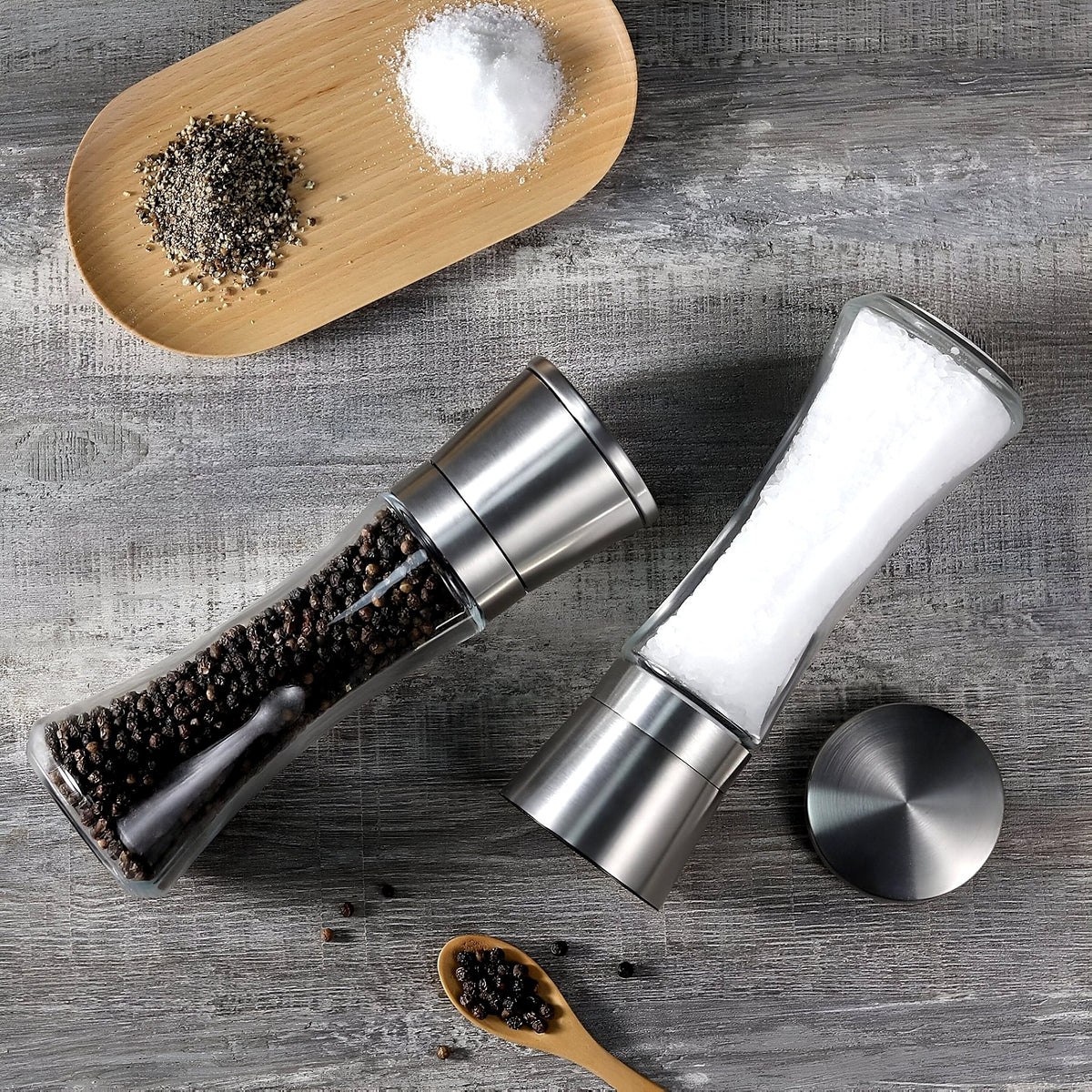 Stainless steel salt and pepper grinders on a table